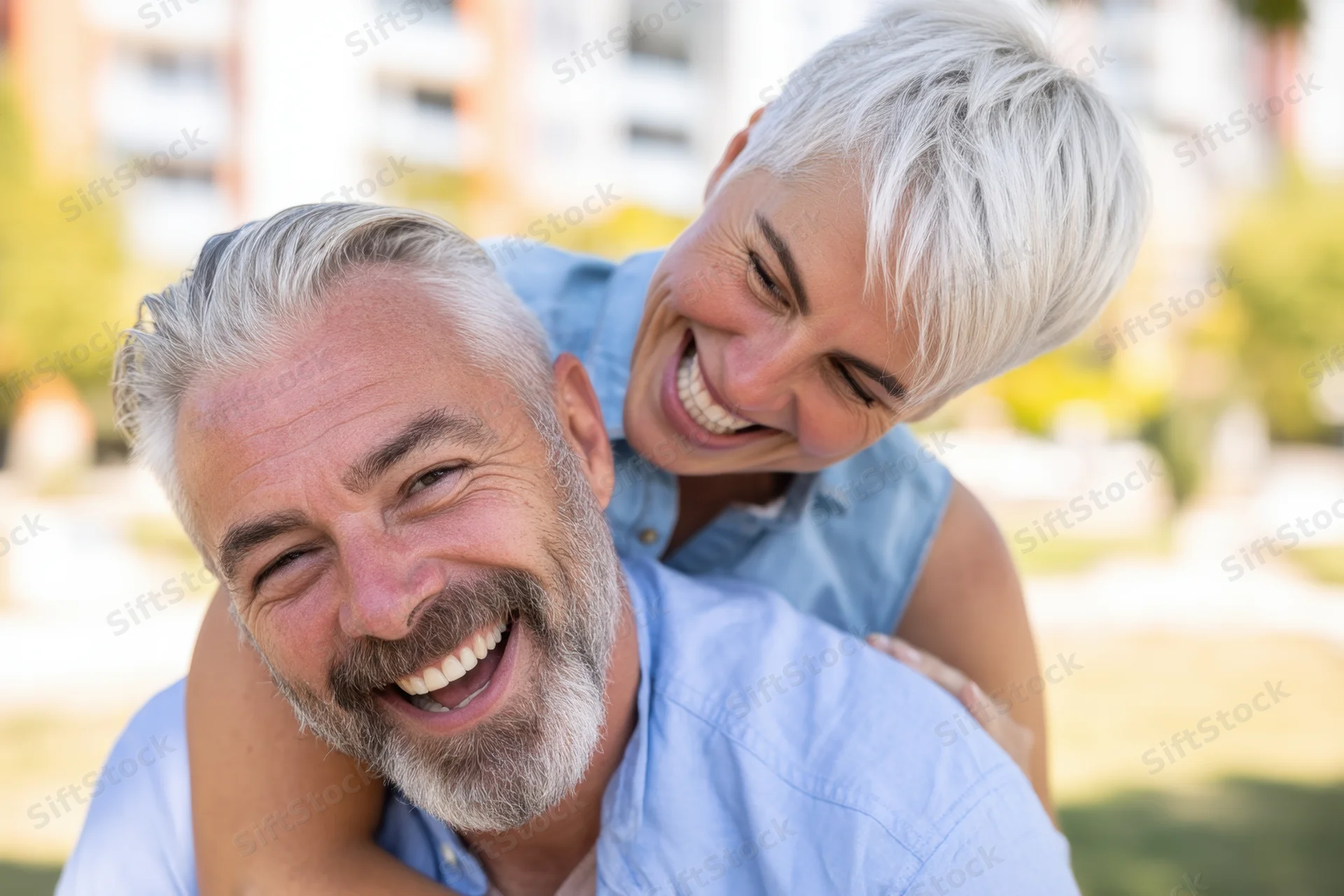 Man carrying woman on his back while both laugh in a park