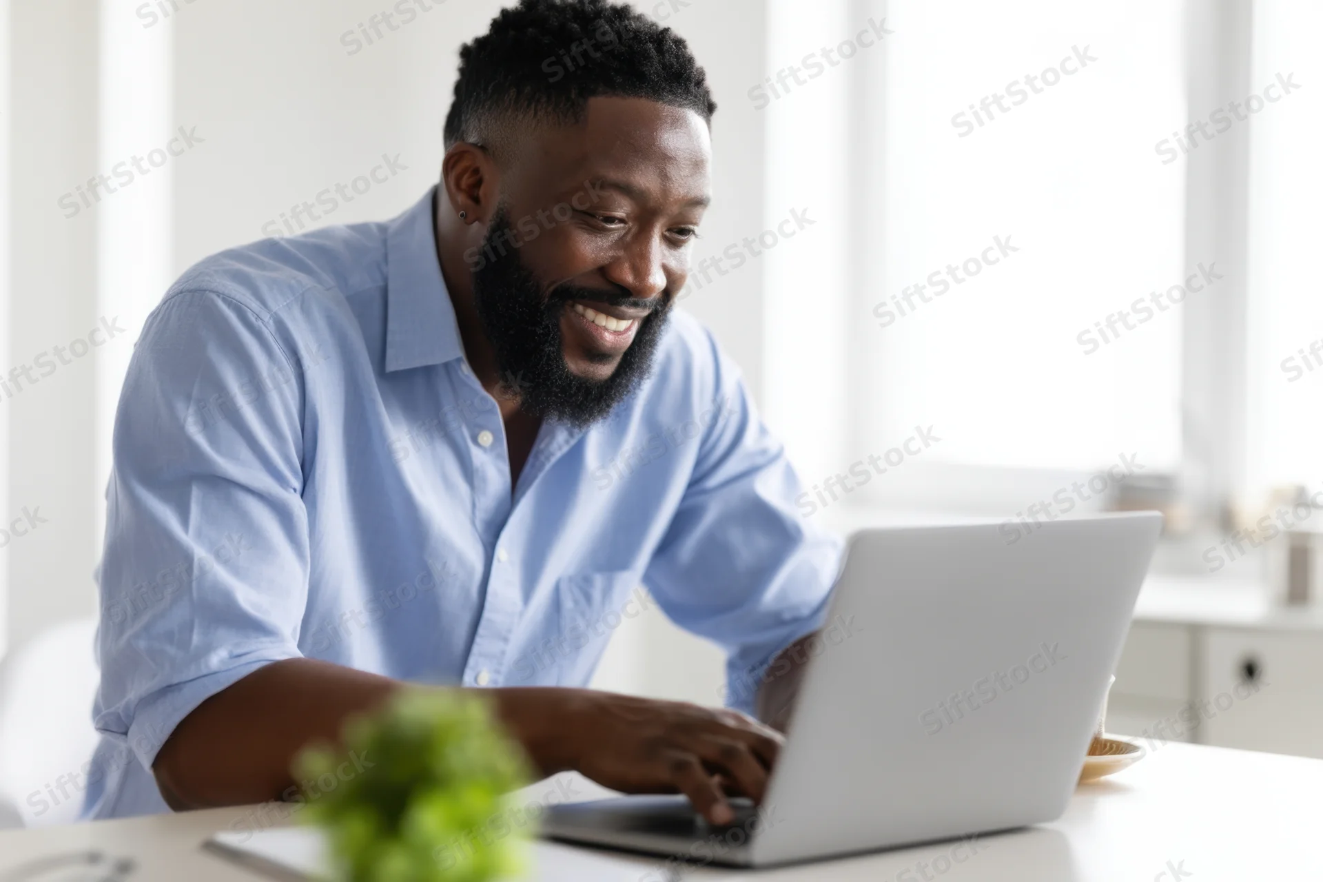 Man smiling while working on laptop at home office desk