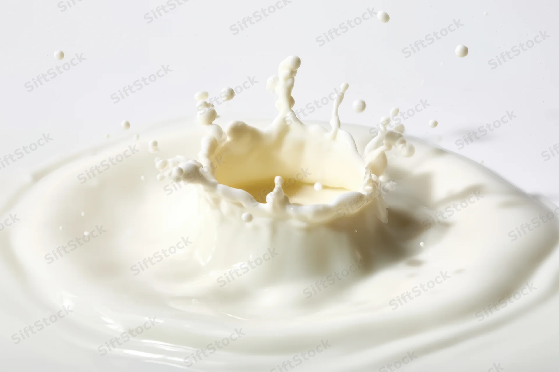 Milk splash forming a crown-shaped droplet crown on a white surface