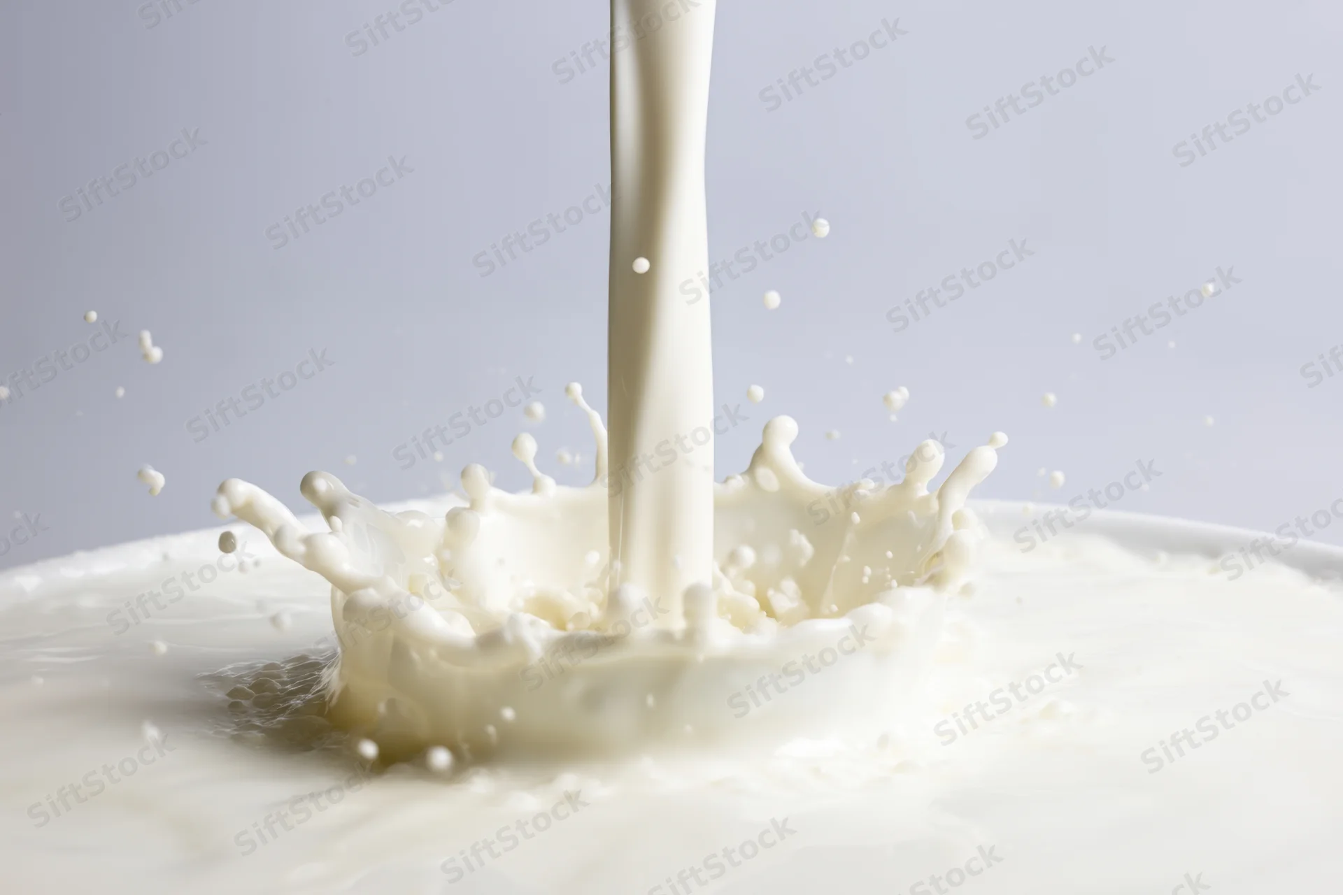 Smooth stream of milk cascading into a pool creating a splash crown