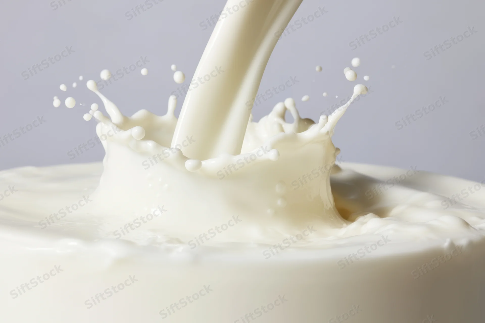Smooth stream of milk cascading into a pool creating a splash crown