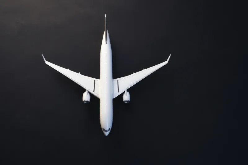 White model airplane viewed from above on matte black surface