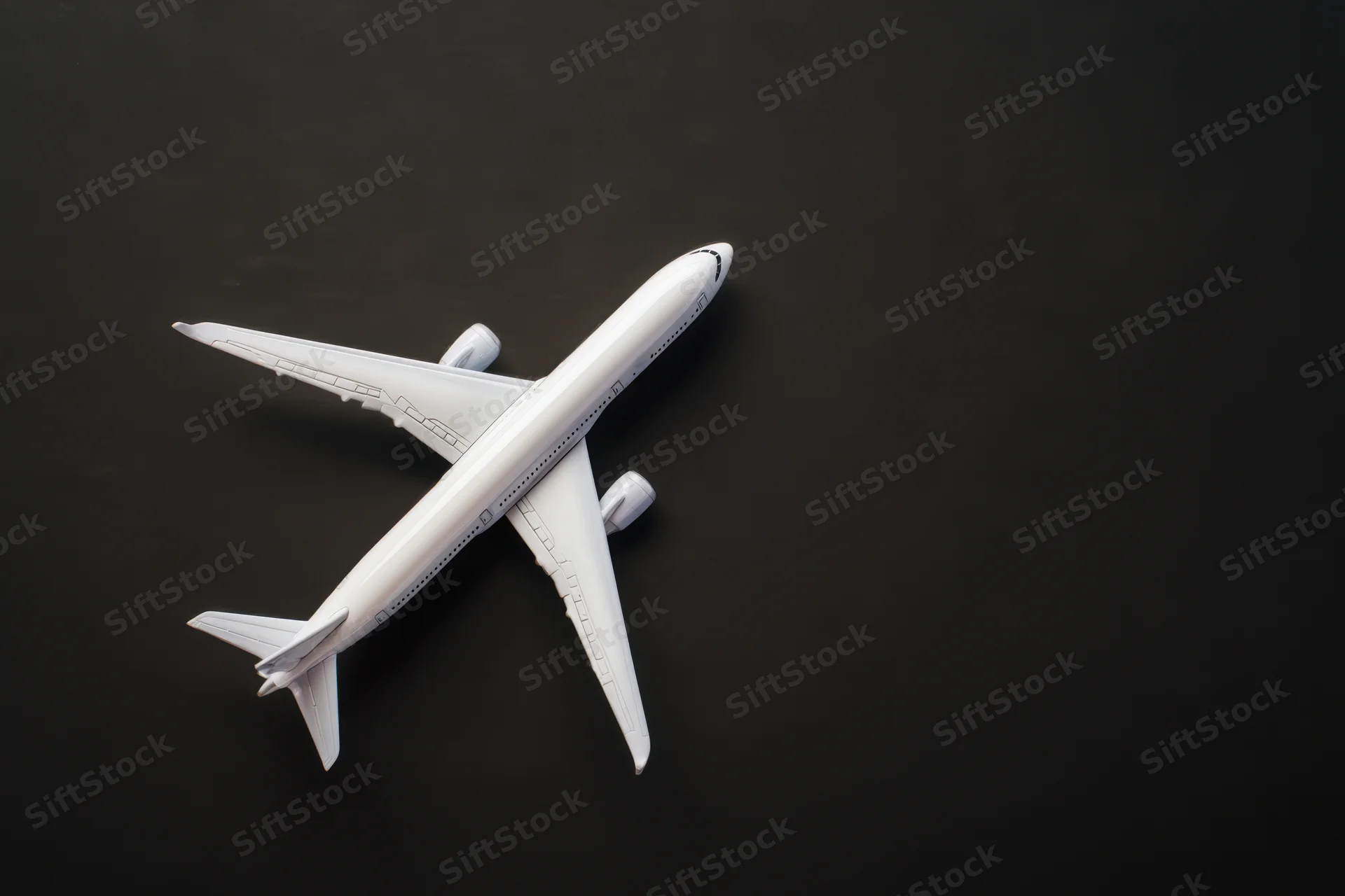 White model airplane positioned flat on matte black surface
