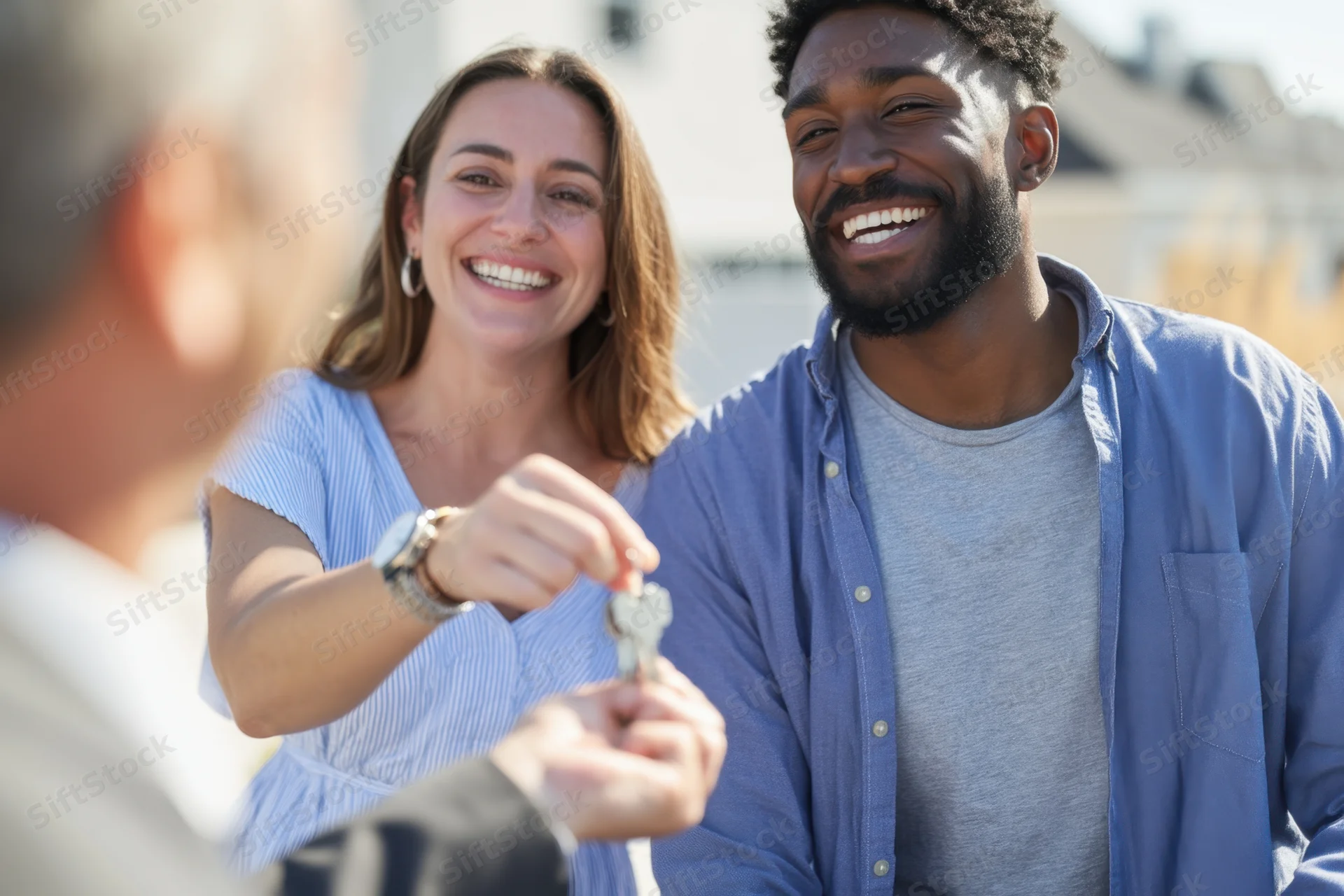 Young couple receiving house keys from realtor in suburban neighborhood