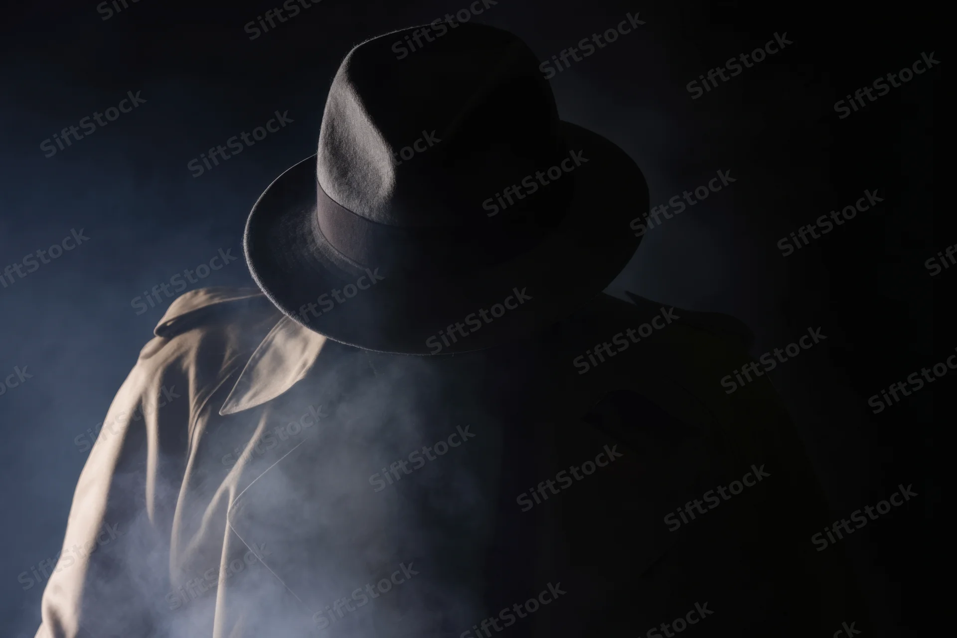 Mysterious figure in trench coat and fedora shrouded in smoke at night