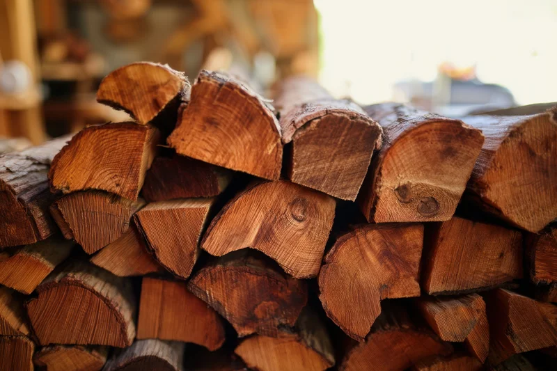 Neatly stacked hardwood logs arranged in a pile for storage and heating use