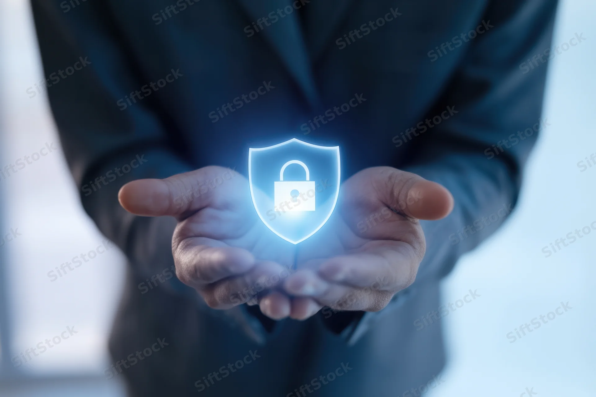 Hands cradling a glowing holographic shield with a lock symbol in an office setting