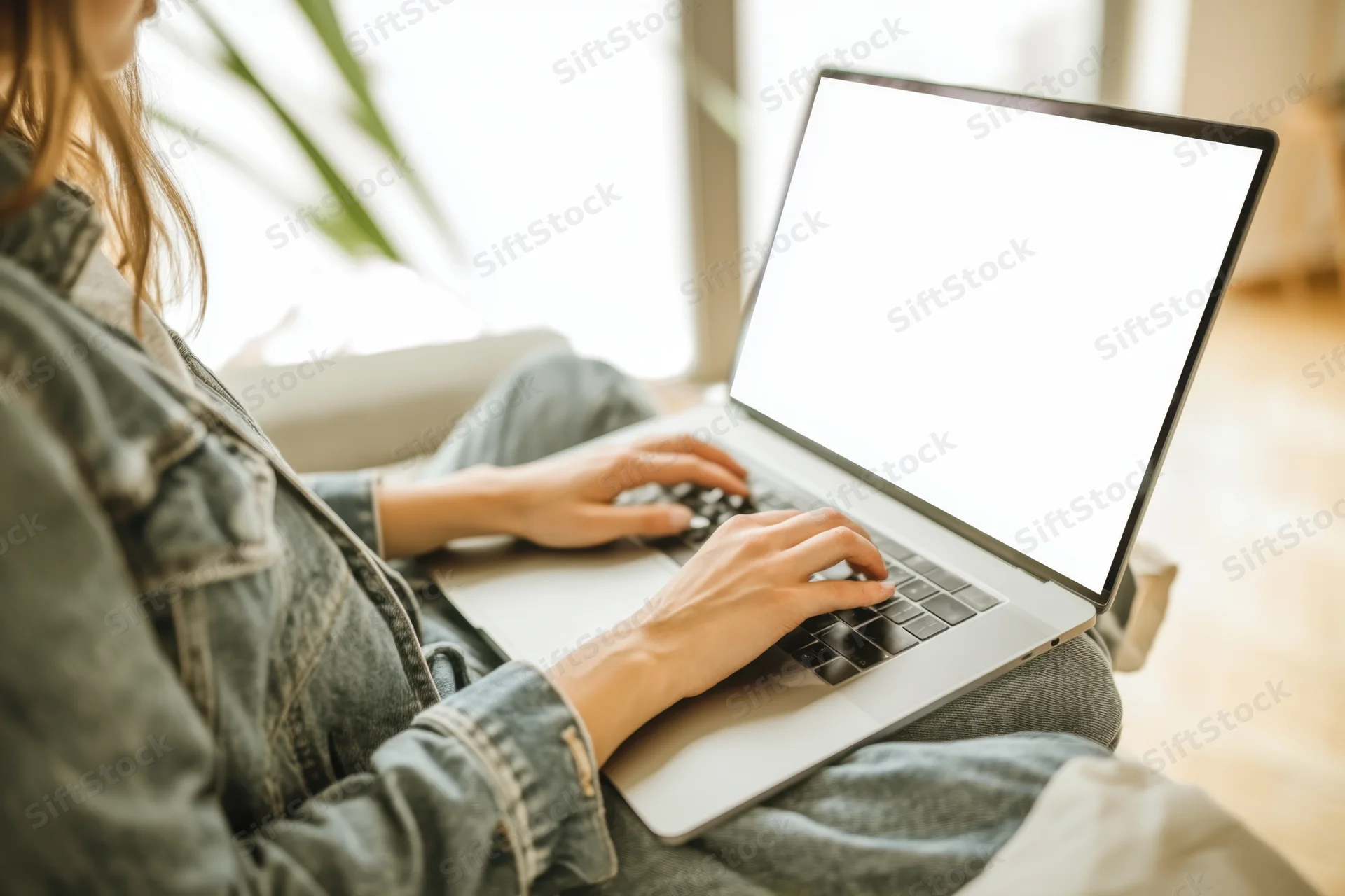 Woman typing on laptop while sitting at home in casual clothing