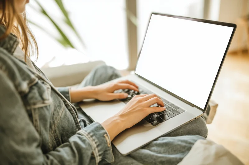 Woman typing on laptop while sitting at home in casual clothing