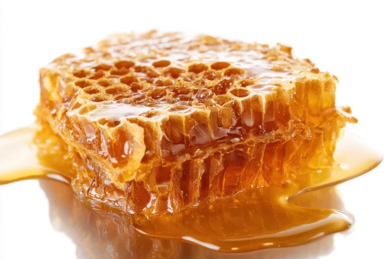 Honeycomb with honey dripping onto a glossy surface