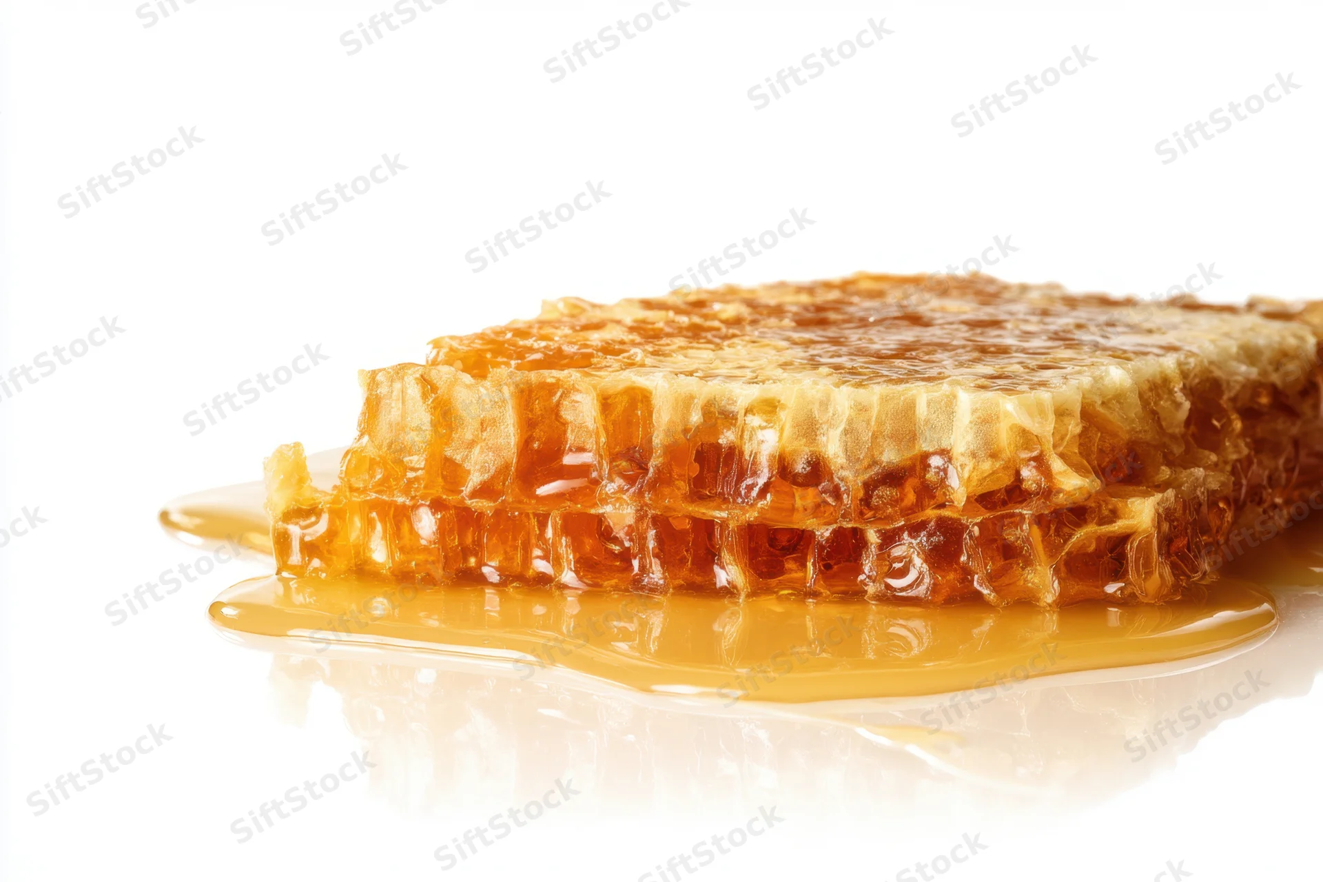 Honeycomb piece resting on glossy surface with honey dripping around it