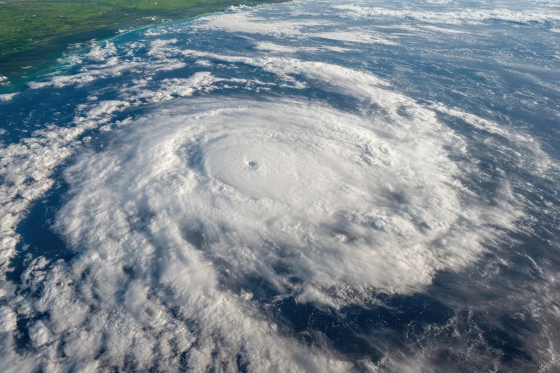 Powerful hurricane swirling over ocean with visible eye and spiral cloud bands near coastline