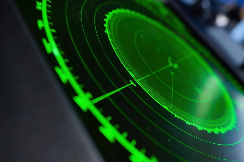 Green radar display showing concentric circles and target indicators on a dark screen
