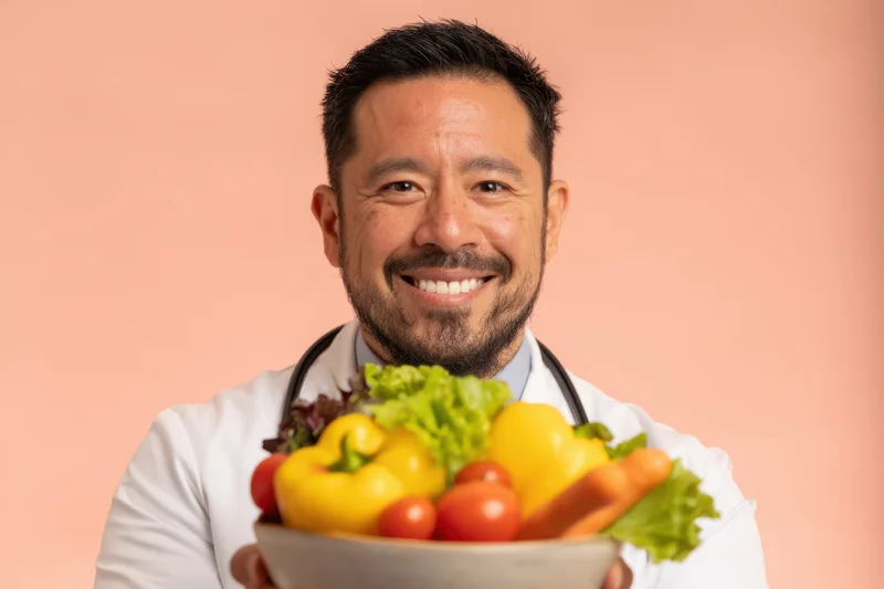 Smiling male doctor in lab coat holding bowl of fresh vegetables in studio