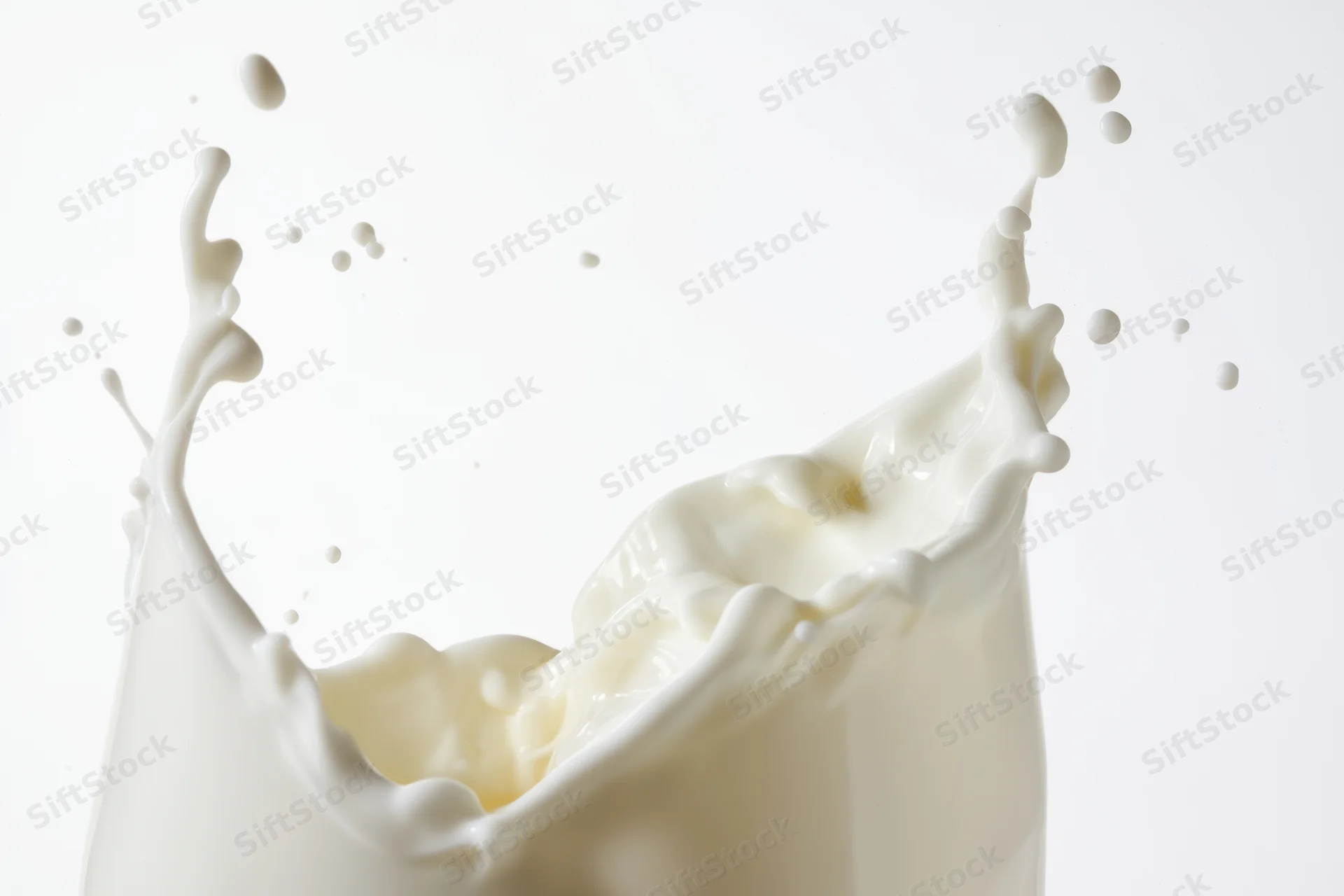 Milk splash forming a crown with flowing waves and airborne droplets against a white background