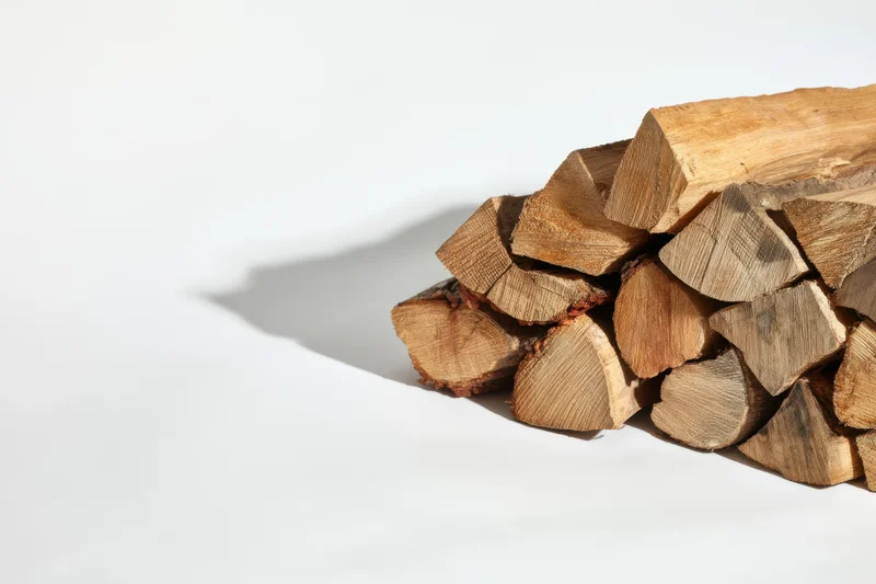 Stacked firewood logs arranged on a white surface with copyspace