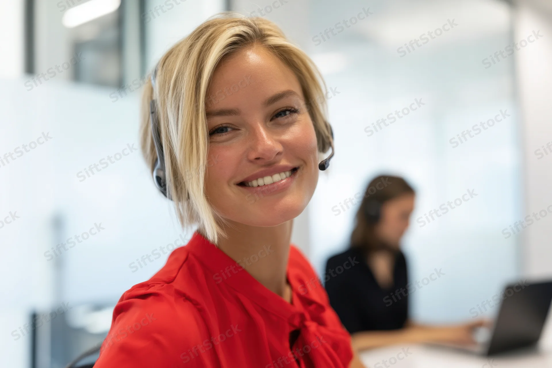 Young woman wearing headset smiling in office call center workspace