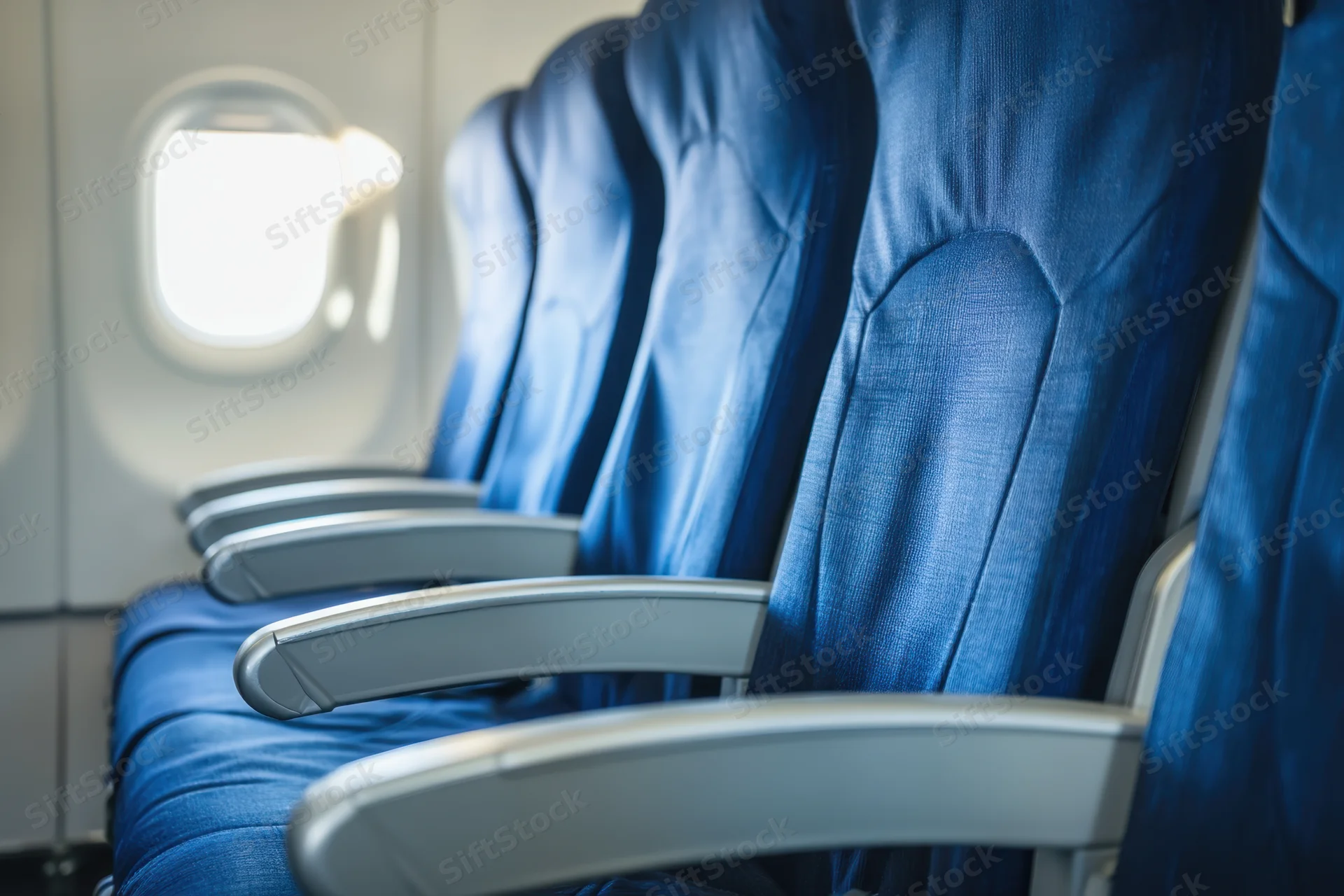 Row of empty blue seats in airplane cabin near window