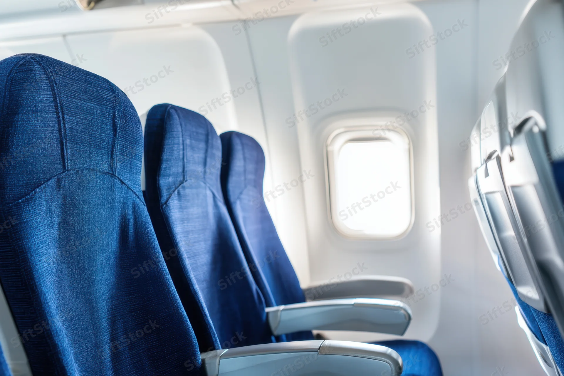 Row of empty blue seats in airplane cabin near window