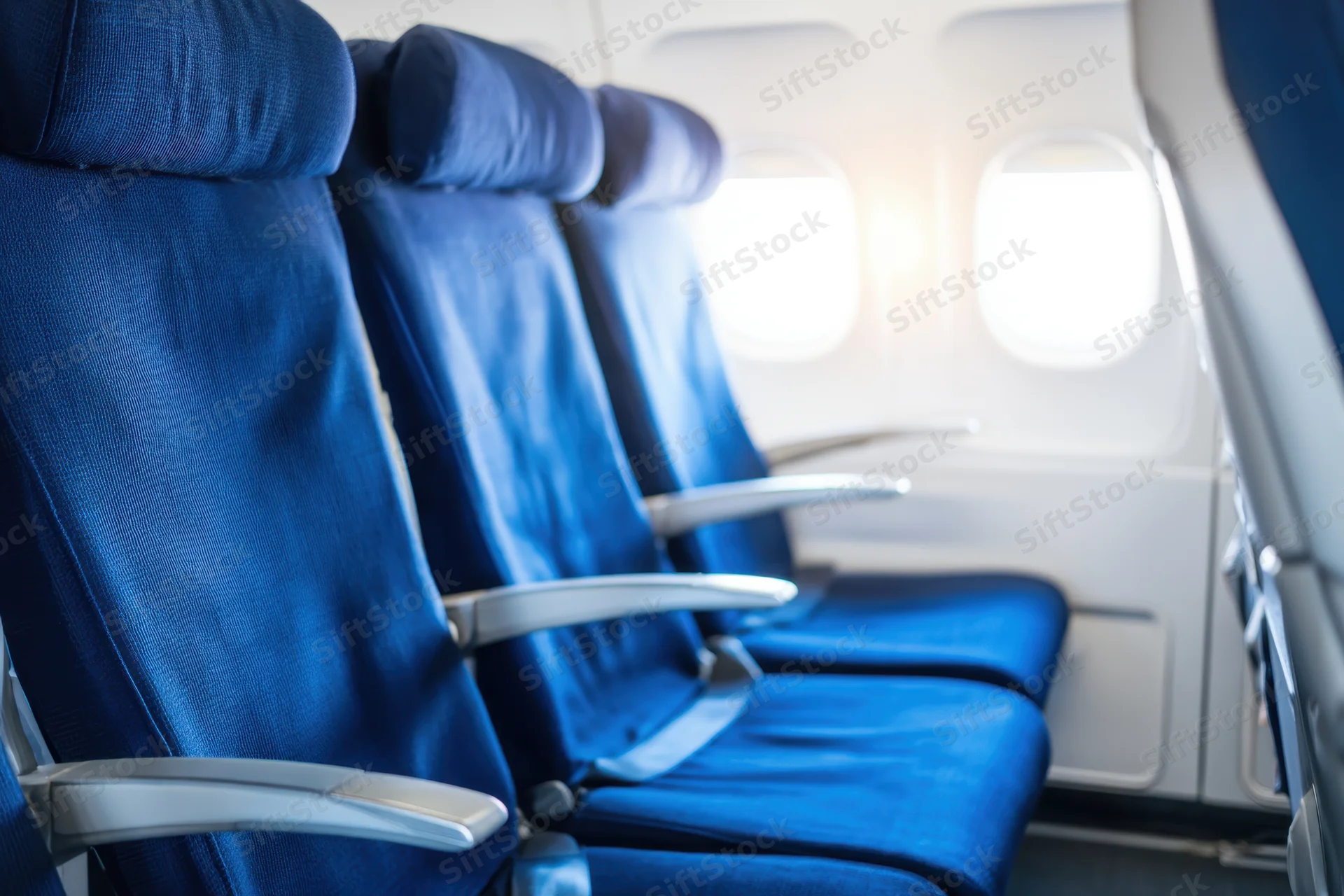 Row of empty blue seats in airplane cabin near window