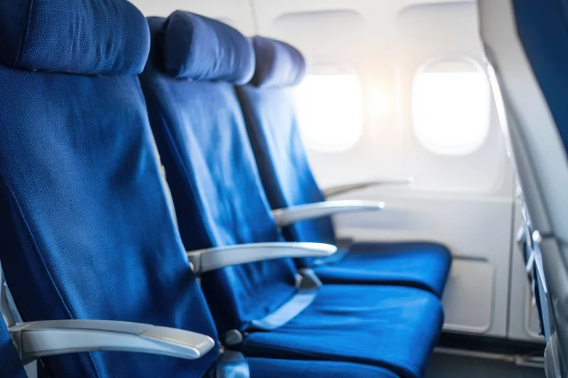 Row of empty blue seats in airplane cabin near window