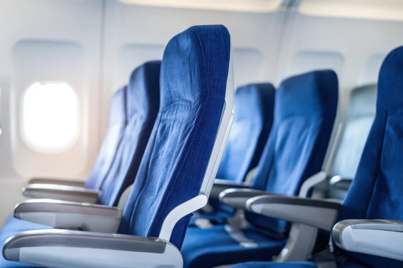 Row of empty blue seats in airplane cabin near window