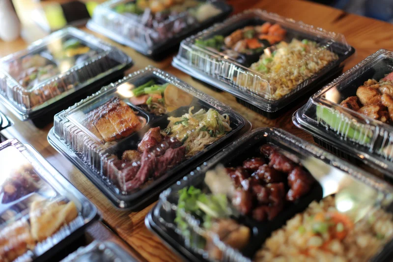 Bento boxes filled with various meals arranged on a wooden table