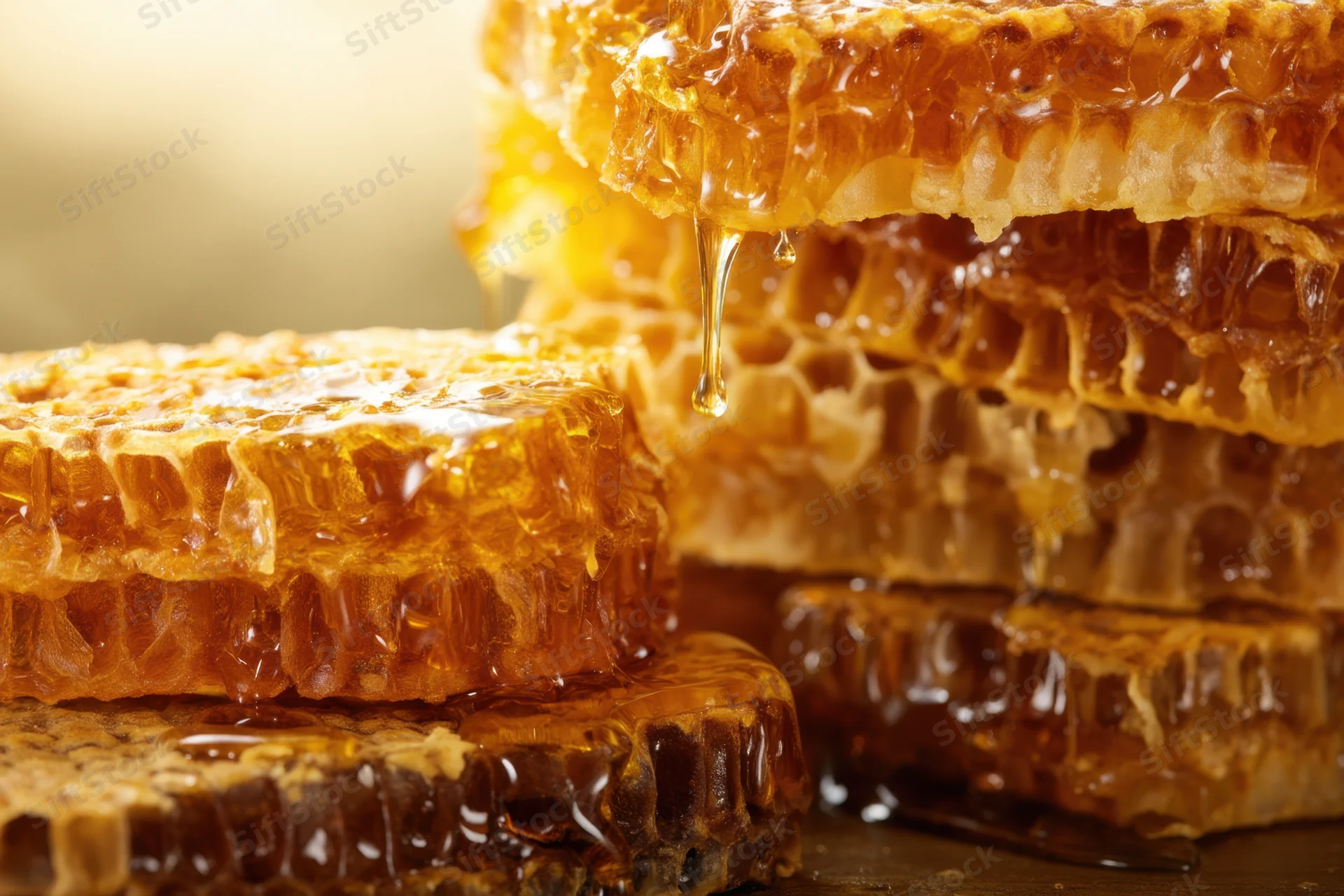 Honeycomb stacks with honey dripping from cells on a dark surface