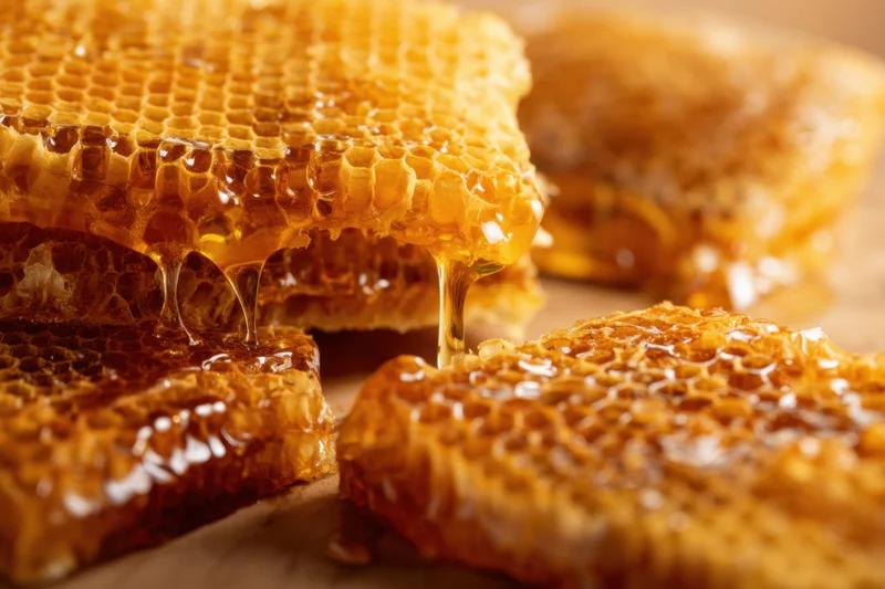 Honeycomb pieces with honey dripping onto a wooden surface