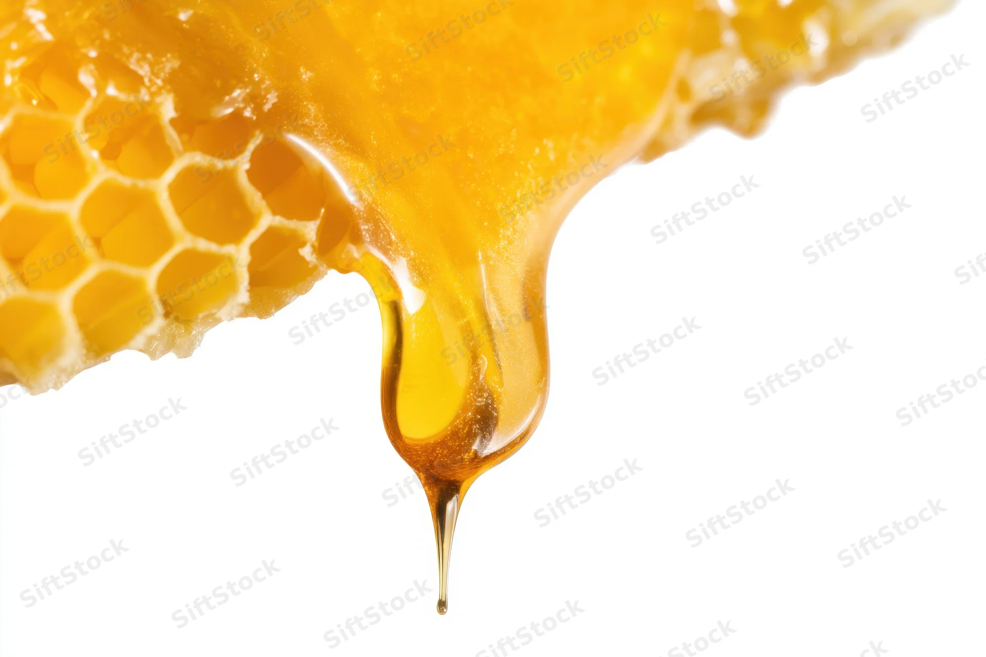 Golden honey dripping from a honeycomb against white background