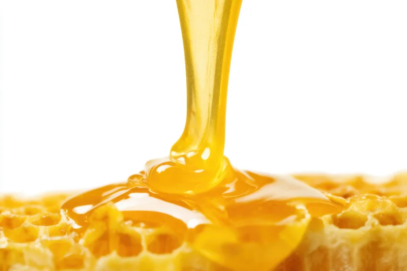 Golden honey dripping thickly from a honeycomb structure