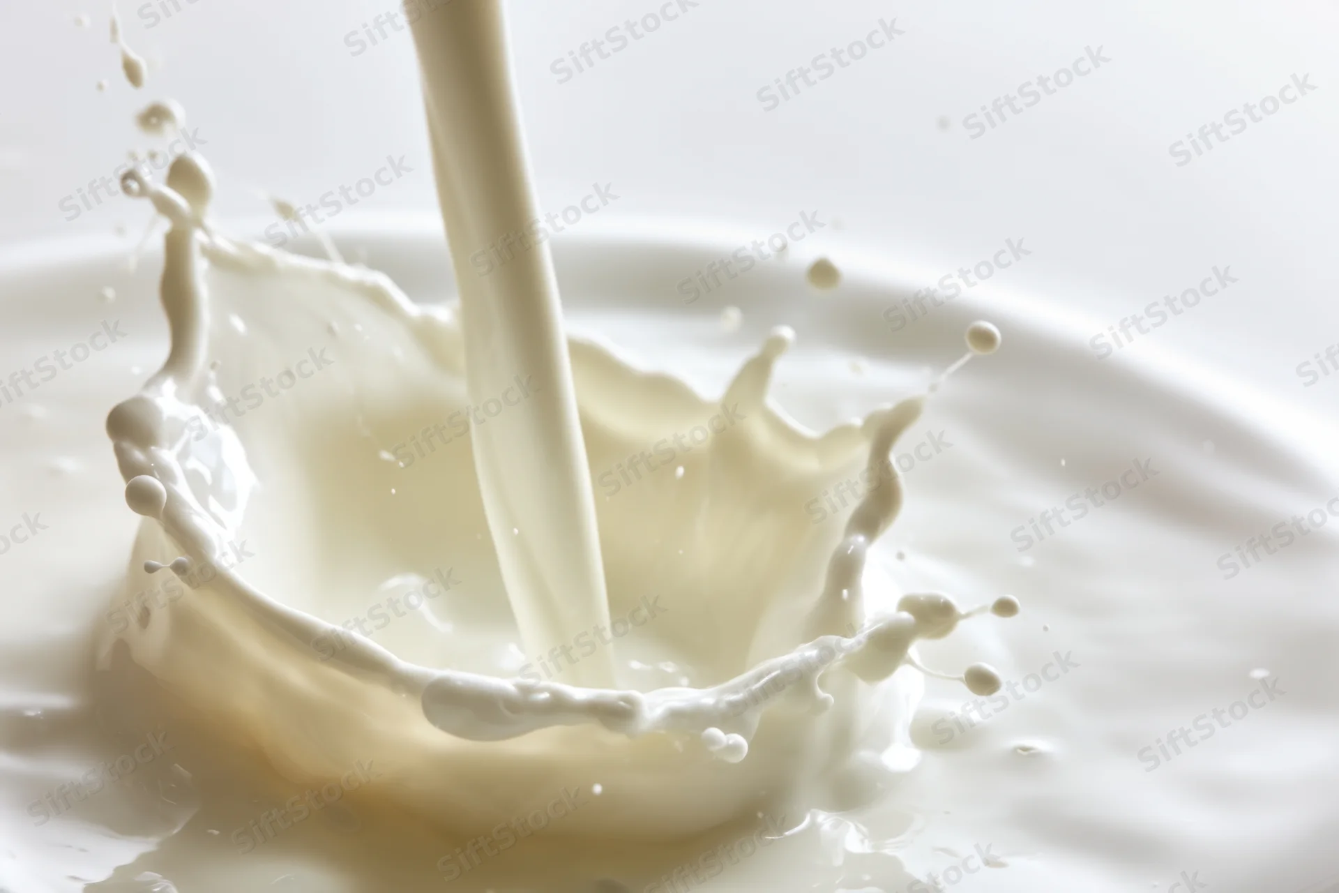 Milk being poured into a pool of milk creating a dynamic splash with crown and droplets