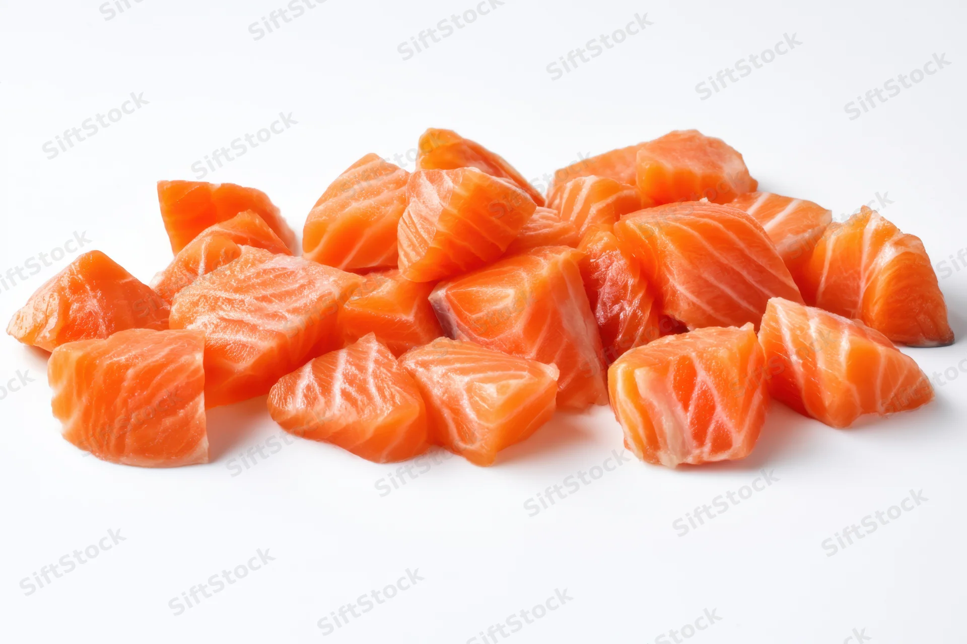 Scattered raw salmon chunks on a white background