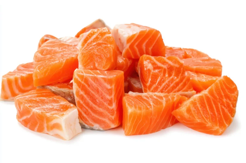 Scattered raw salmon chunks on a white background