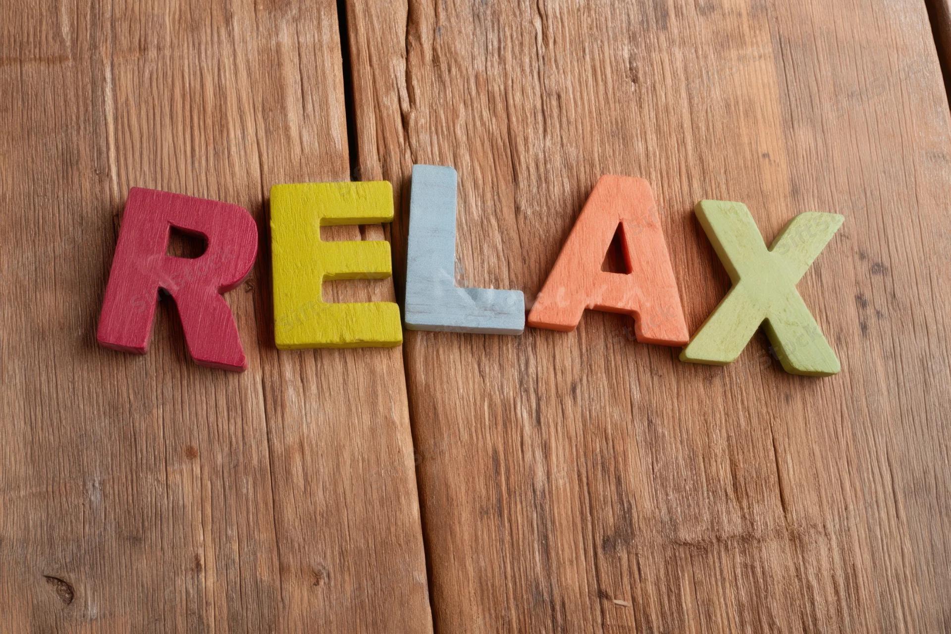 Colorful wooden letters spelling relax arranged on a wooden surface