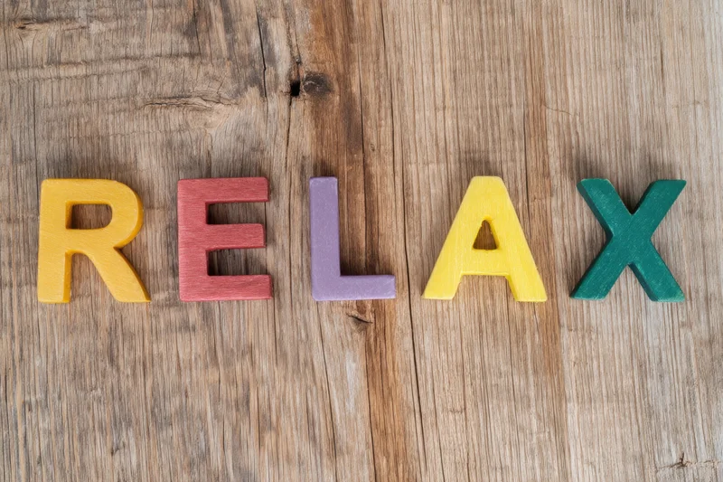 Colorful wooden letters spelling relax arranged on a rustic wood surface