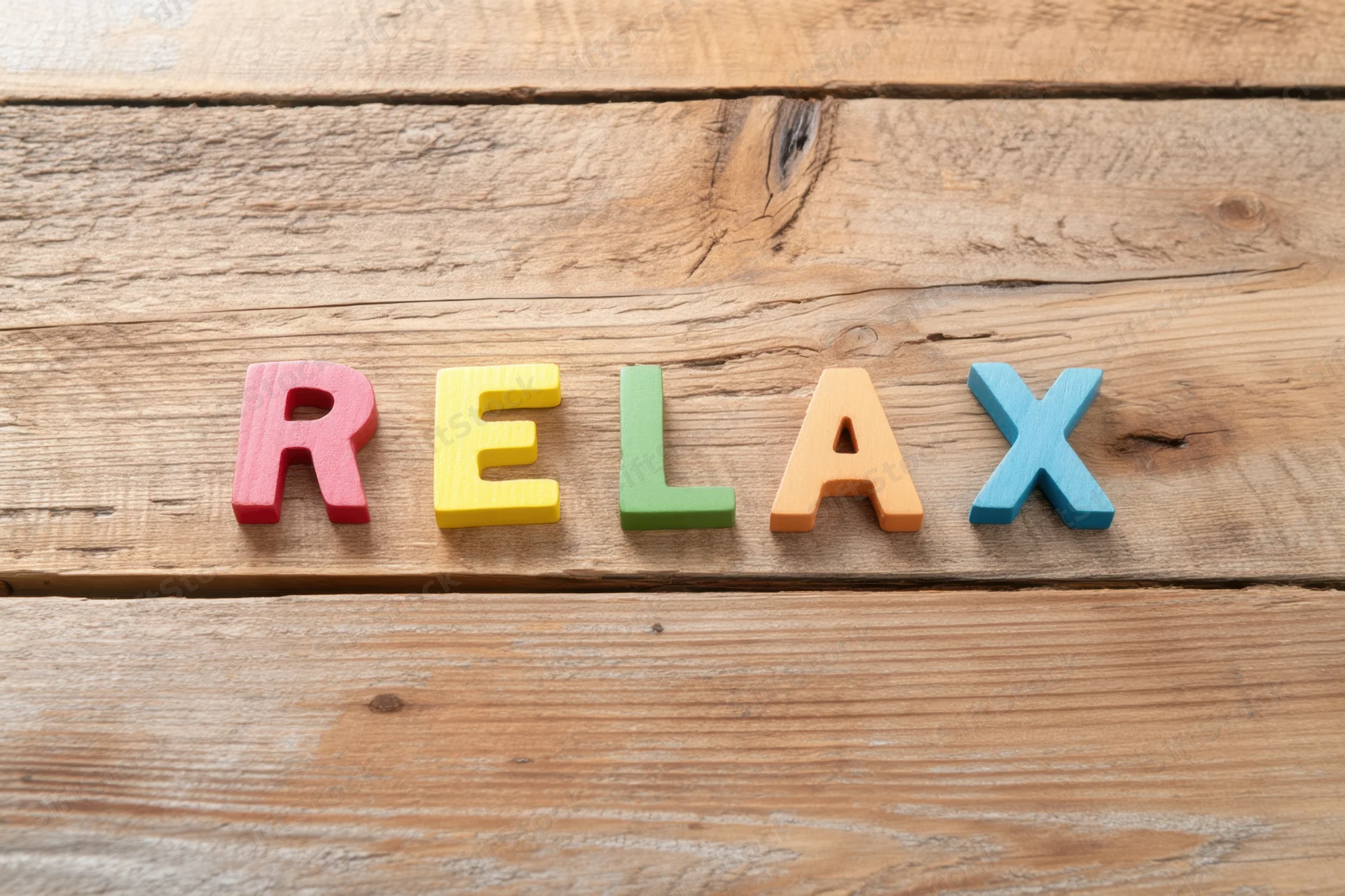 Colorful wooden letters spelling relax arranged on a rustic wooden surface