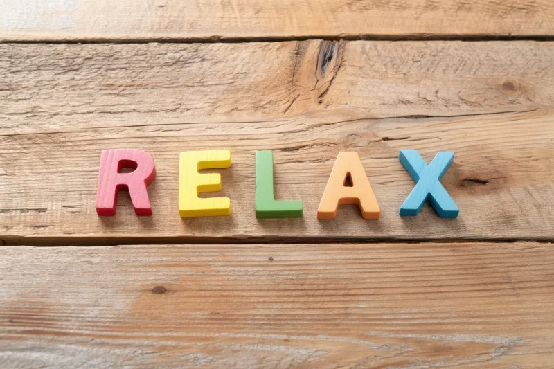 Colorful wooden letters spelling relax arranged on a rustic wooden surface