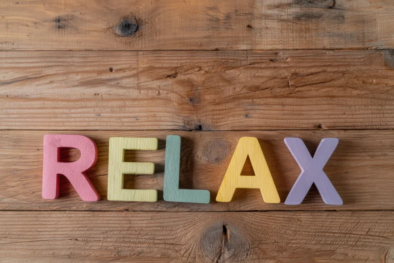 Colorful wooden letters spelling relax arranged on a rustic wooden surface
