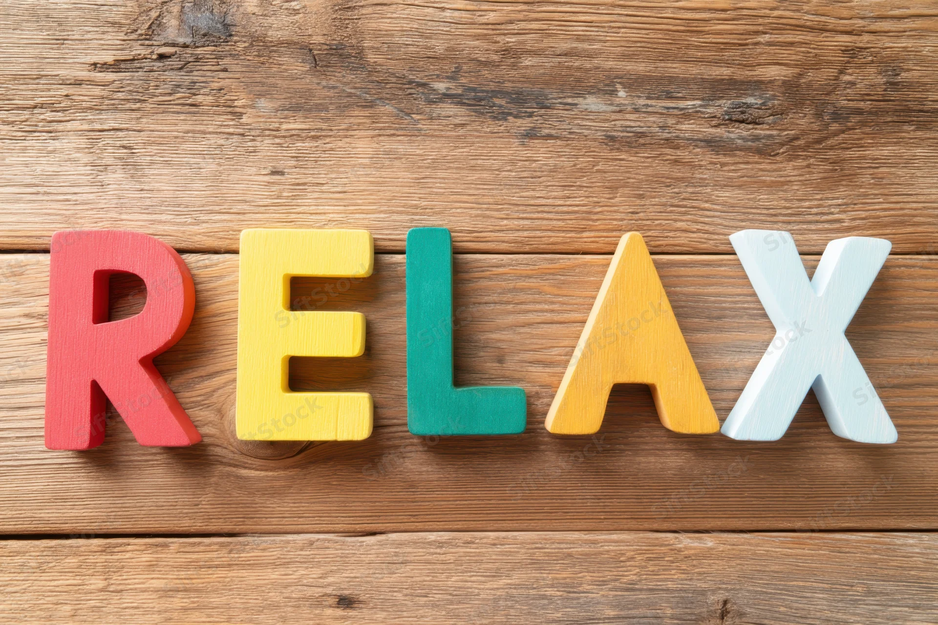 Colorful wooden letters spelling relax arranged on a rustic wood surface