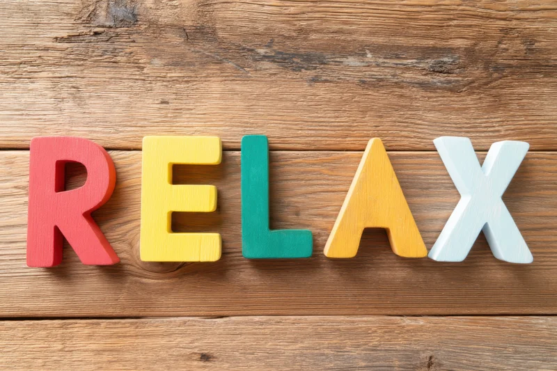Colorful wooden letters spelling relax arranged on a rustic wood surface