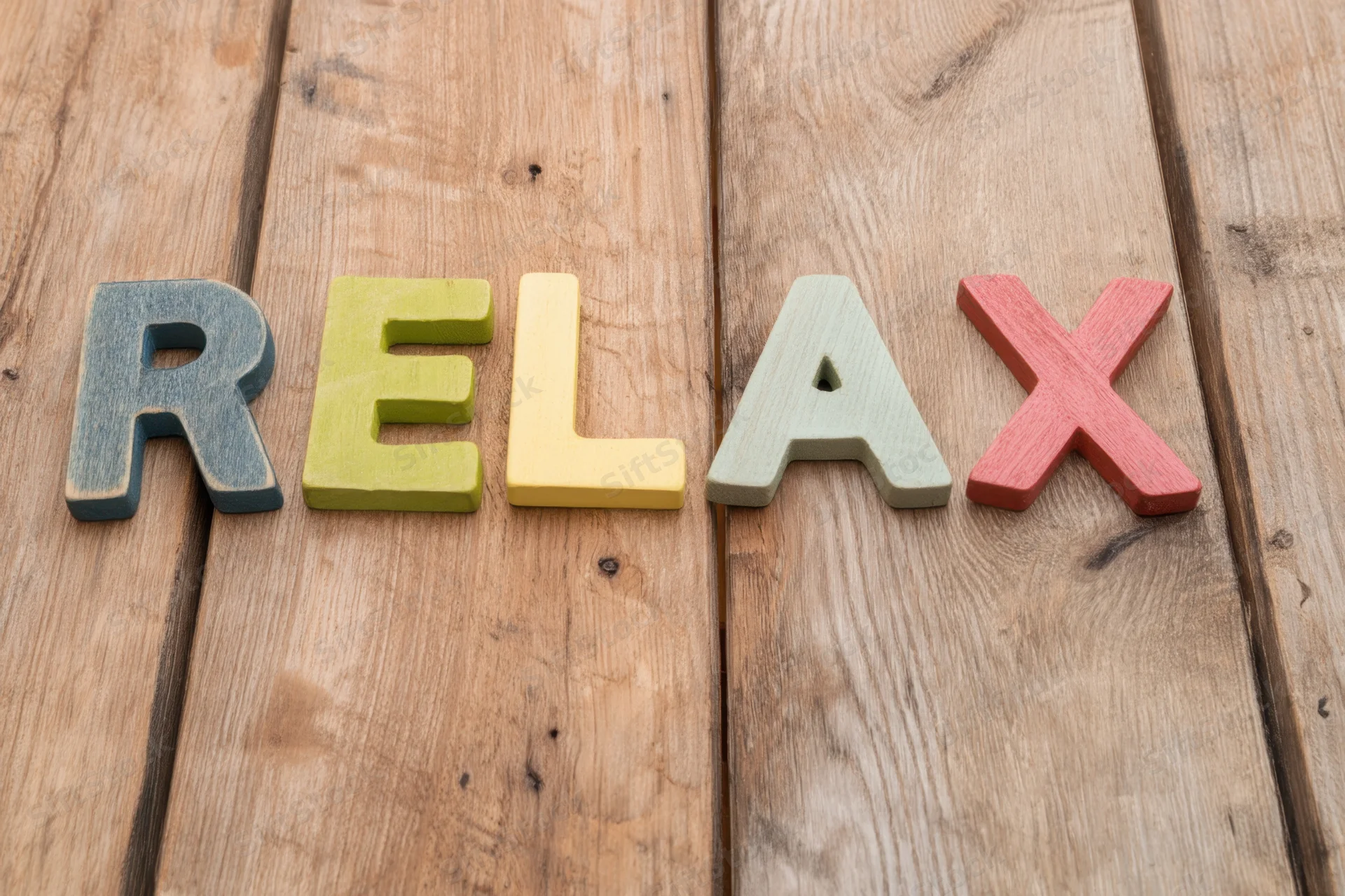 Colorful wooden letters spelling relax arranged on a rustic wooden surface