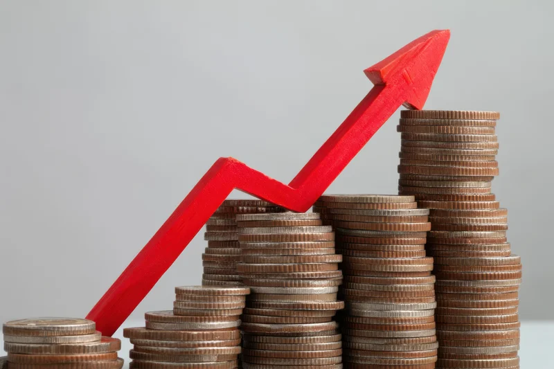 Stacked coins arranged in ascending order with a red arrow pointing upward across them
