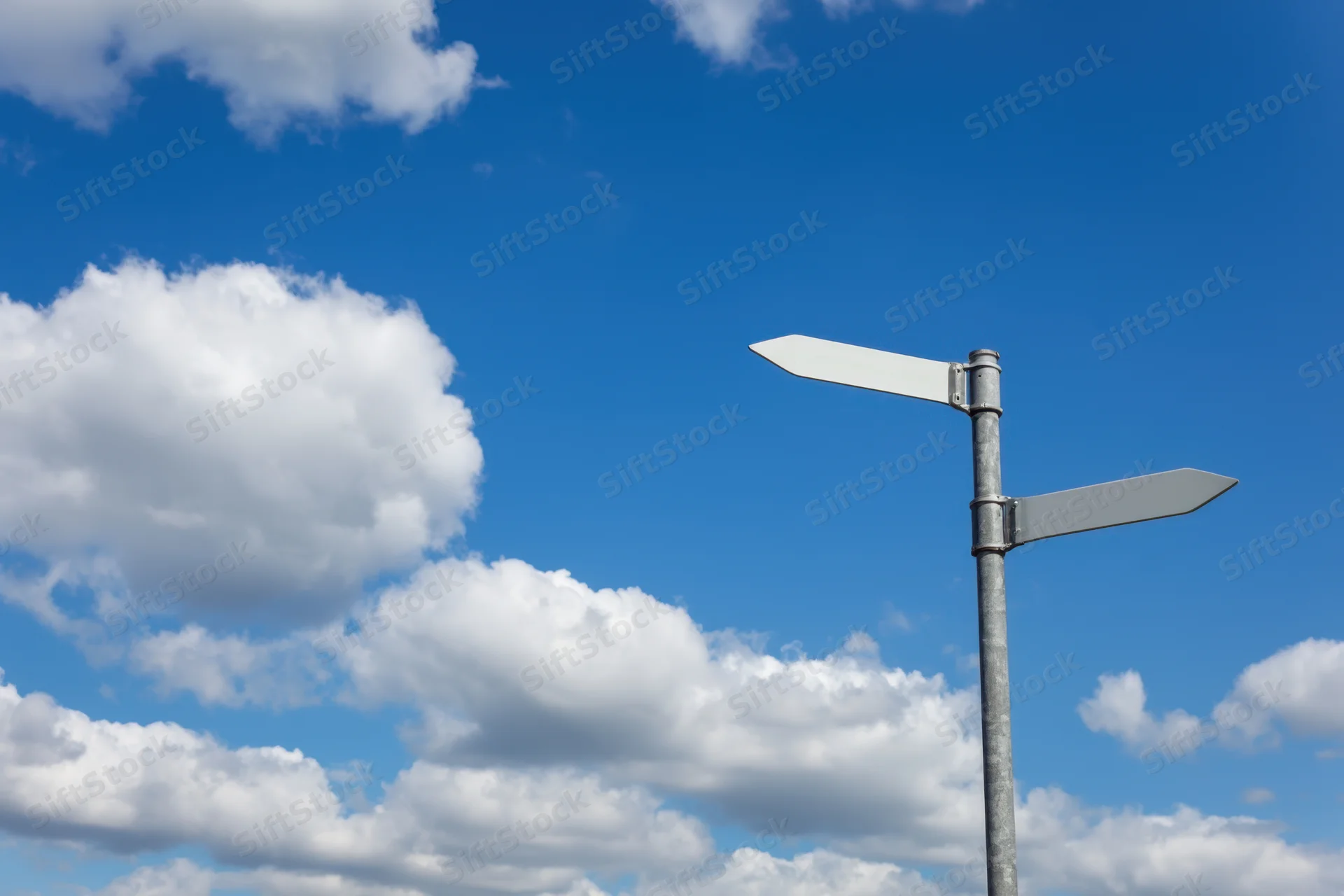 Blank metal sign with two directional arms pointing against a blue sky with white clouds