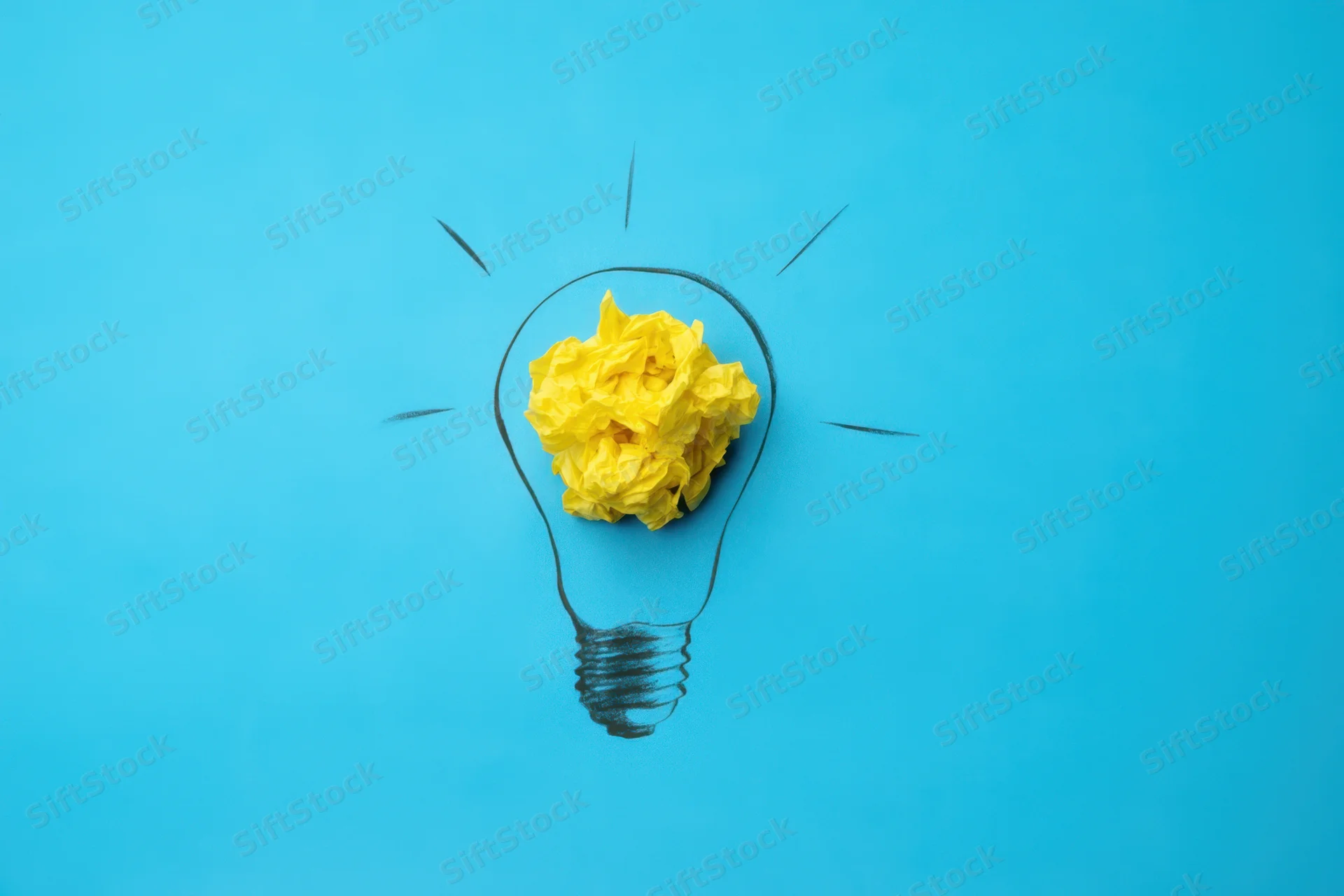 Crumpled yellow paper inside a hand-drawn lightbulb on a blue background