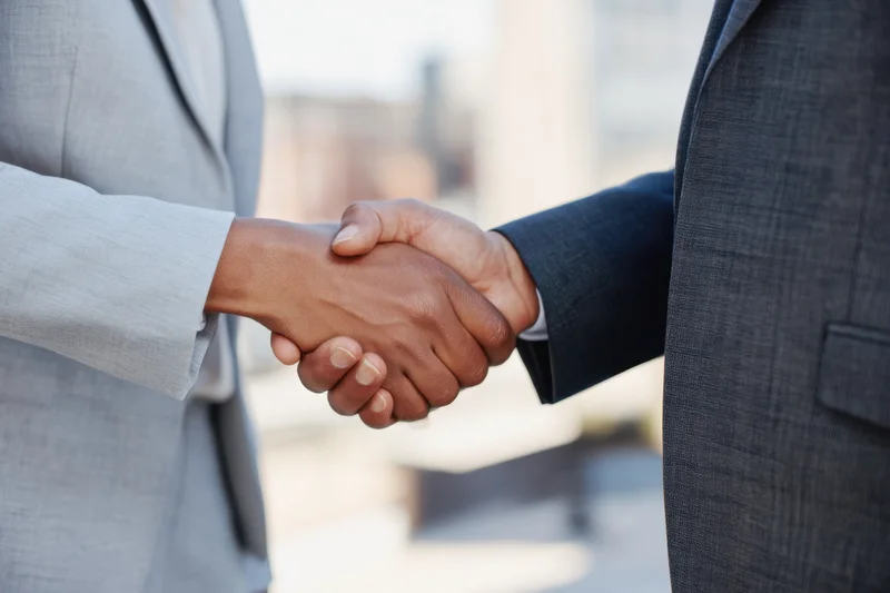 Close-up of two business professionals shaking hands in an office setting