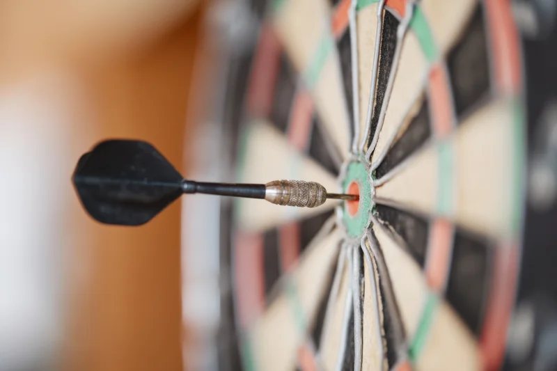 Dart embedded in the bullseye of a dartboard with shallow depth of field and blurred background