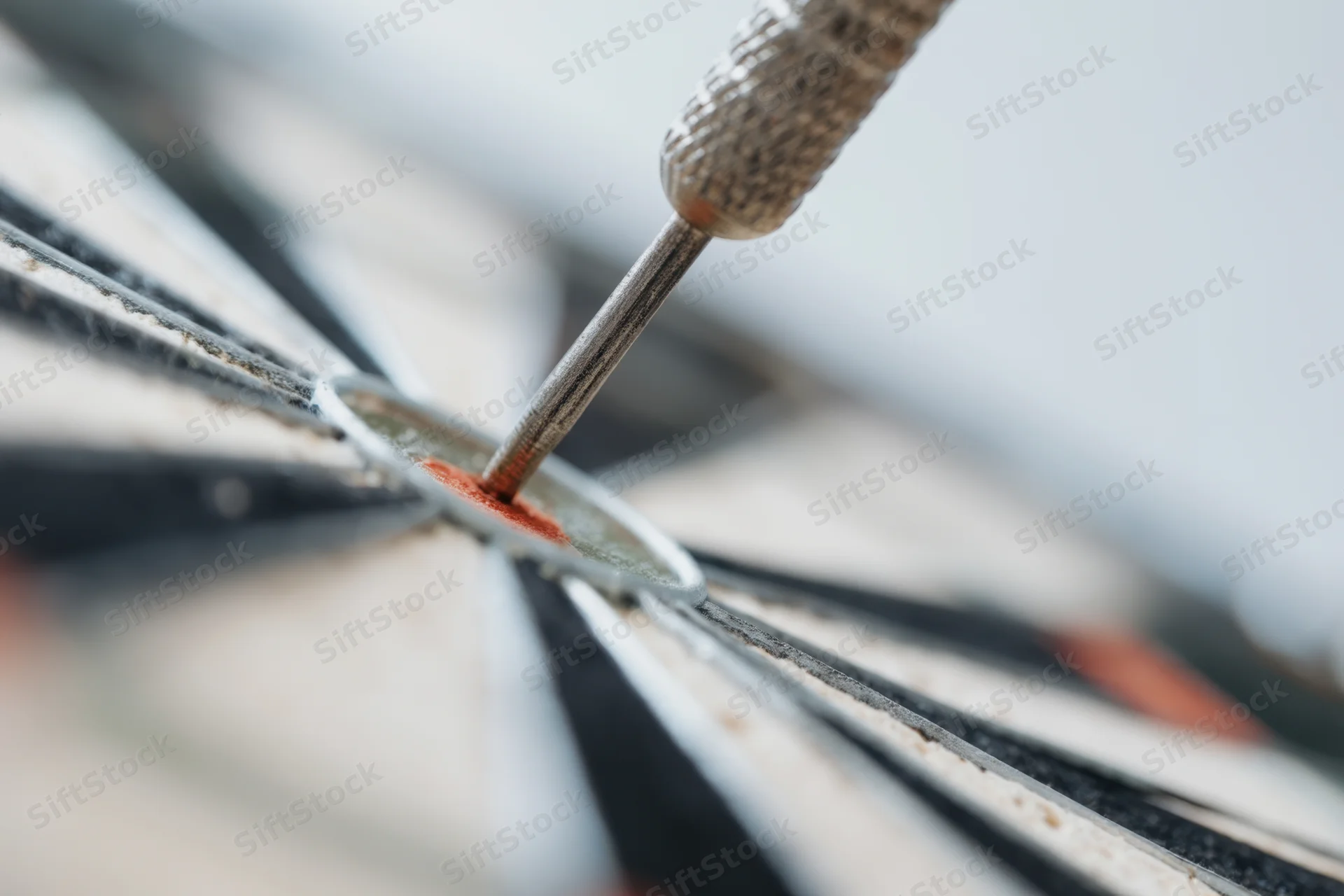Dart embedded in bullseye of dartboard, close-up view