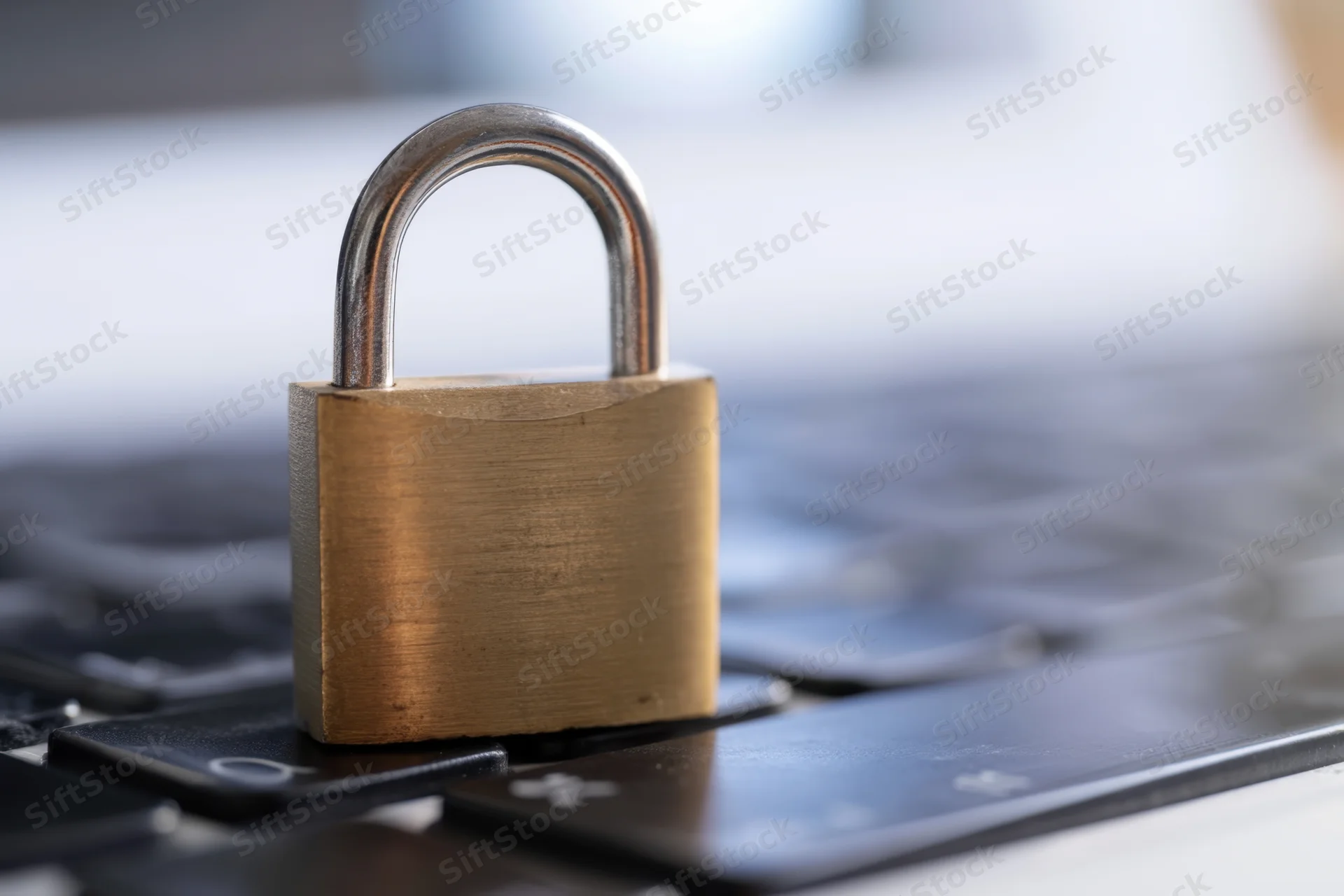 Brass padlock resting on laptop keyboard surface