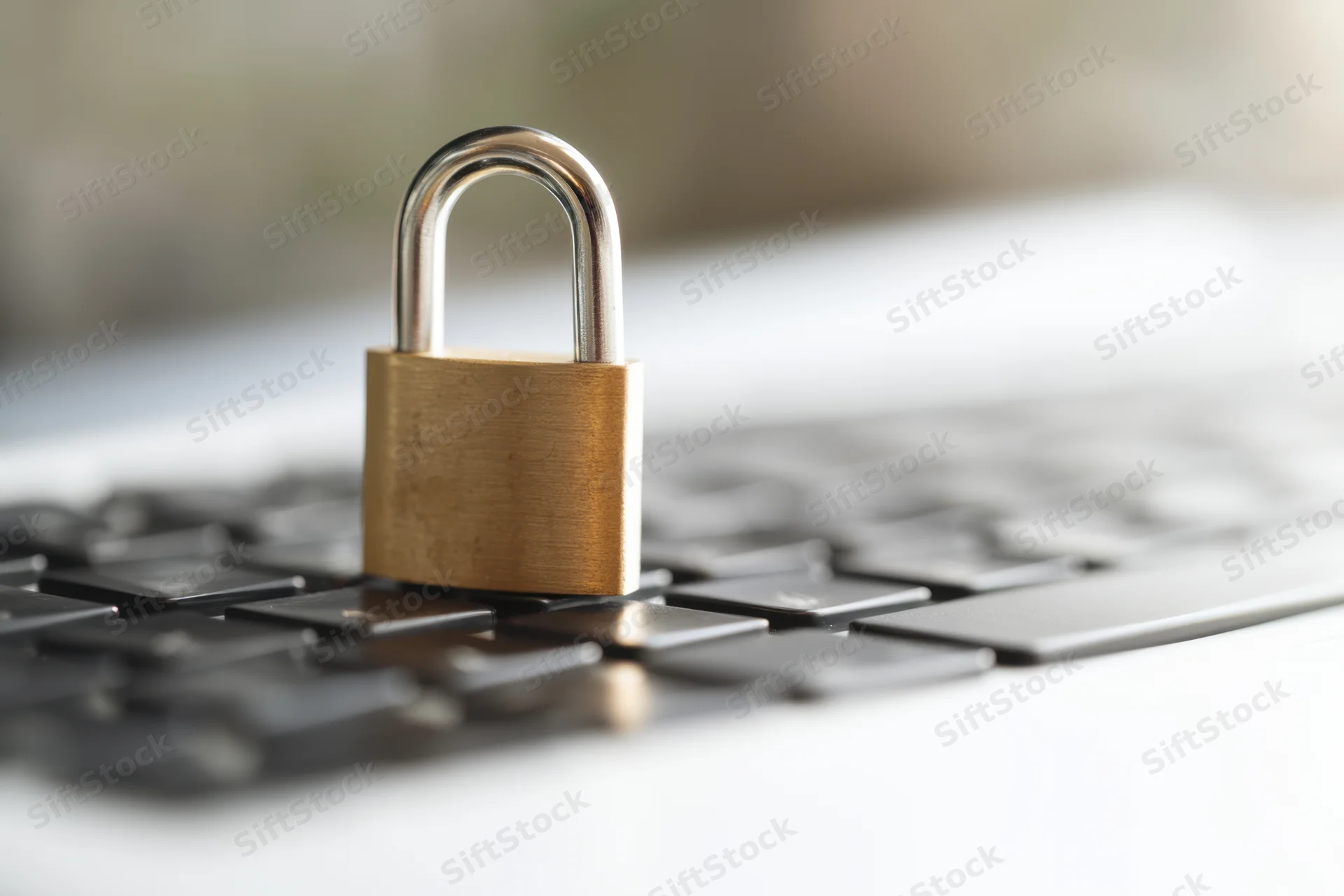 Brass padlock resting on laptop keyboard surface